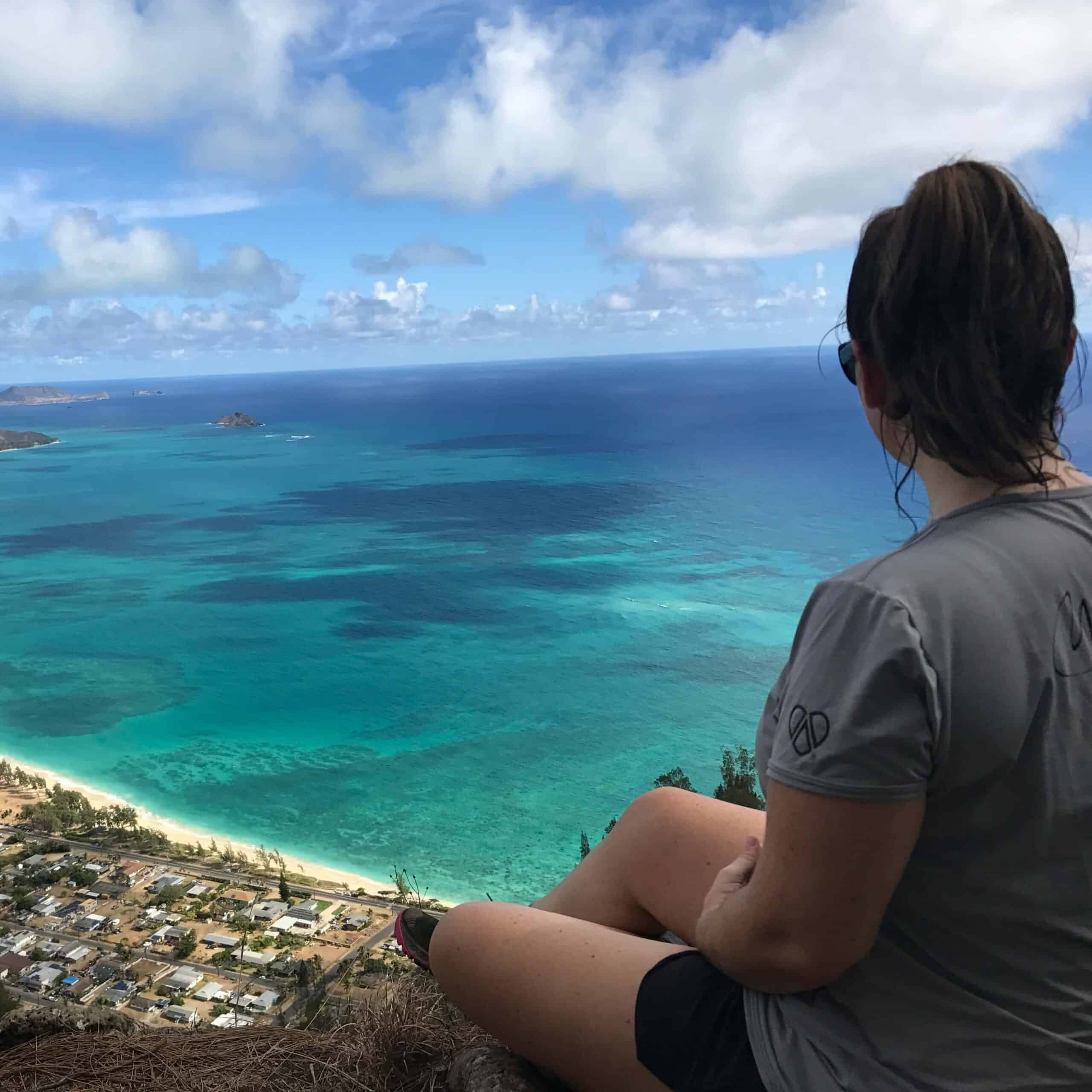 Image of author overlooking a scenic viewpoint showing the blue and green ocean of Hawaii from above.