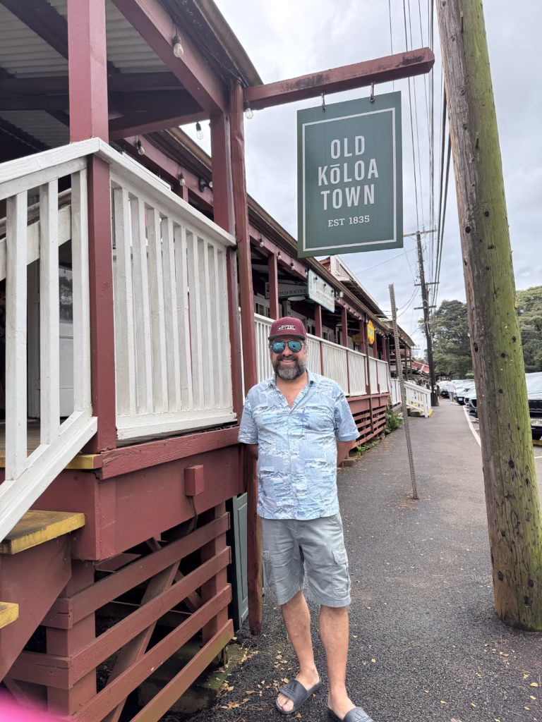 Man standing in front of sign that reads "Old Koloa Town Est. 1835"