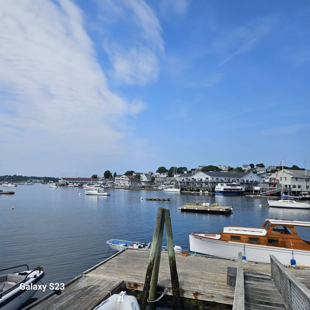 Boothbay Harbor Restaurants - view of the harbor from a dock with fishing boats and hotels in the distance.